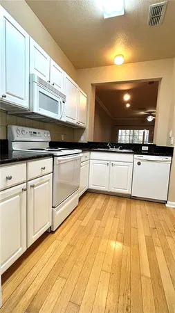 a kitchen with stainless steel appliances granite countertop a sink and cabinets with wooden floor