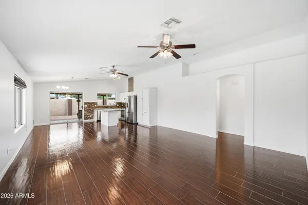 a view of a livingroom with furniture wooden floor a ceiling fan and windows