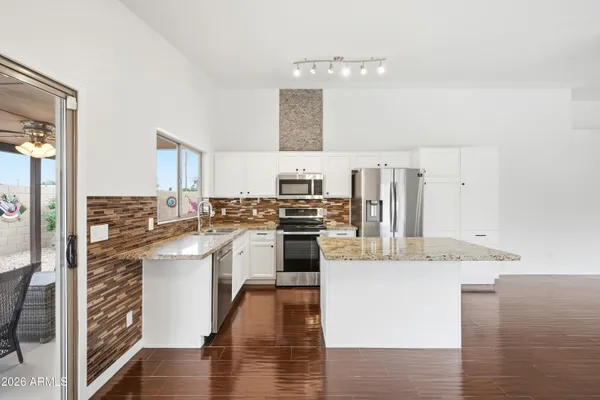 a kitchen with stainless steel appliances granite countertop a stove top oven a sink and white cabinets