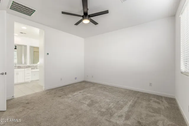 an empty room with closet and a ceiling fan