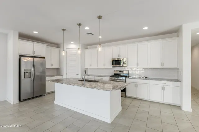 a large kitchen with stainless steel appliances kitchen island granite countertop a stove a sink and a refrigerator