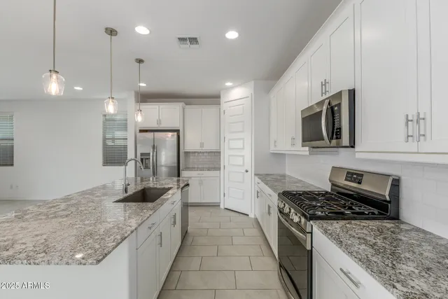 a kitchen with stainless steel appliances granite countertop a sink stove and refrigerator