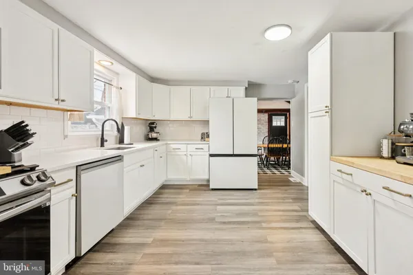 a large white kitchen with cabinets appliances a sink and a window