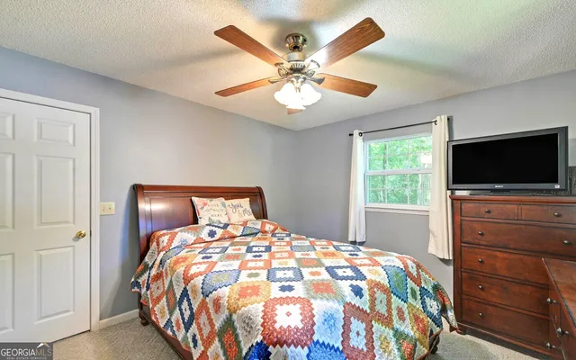 a bedroom with a bed and a flat tv screen on dresser