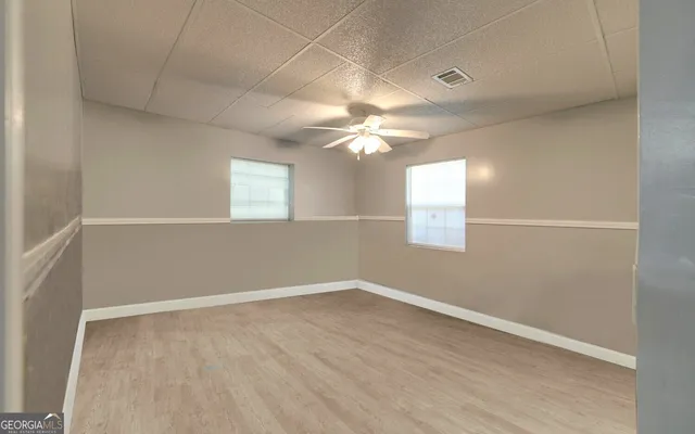 an empty room with windows and fan
