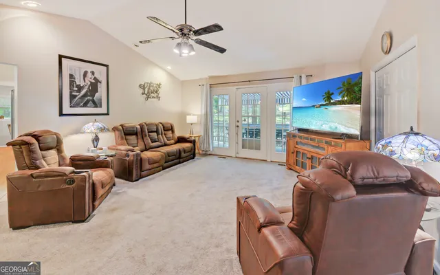 a living room with furniture a flat screen tv and a large window