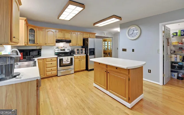 a kitchen with stainless steel appliances granite countertop a stove a sink dishwasher and a refrigerator with wooden floor