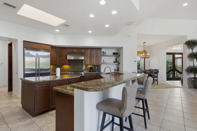 a dining hall with stainless steel appliances granite countertop a table and chairs