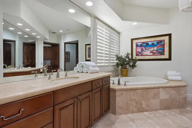 a bathroom with a sink double vanity granite tub shower and a mirror