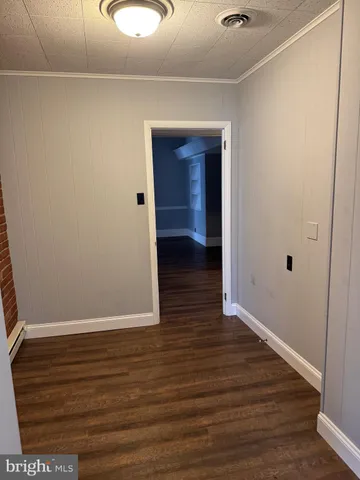 a view of an empty room with wooden floor and closet