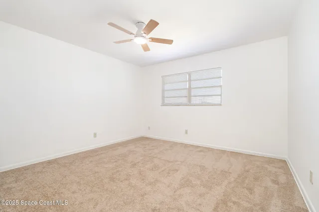 an empty room with a ceiling fan and a window