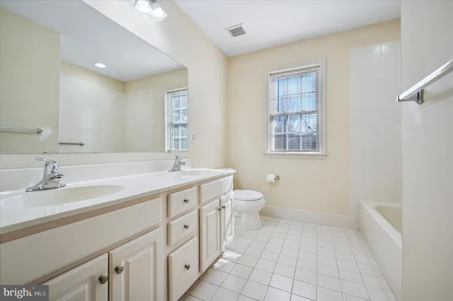 a spacious bathroom with a granite countertop sink a toilet and a mirror