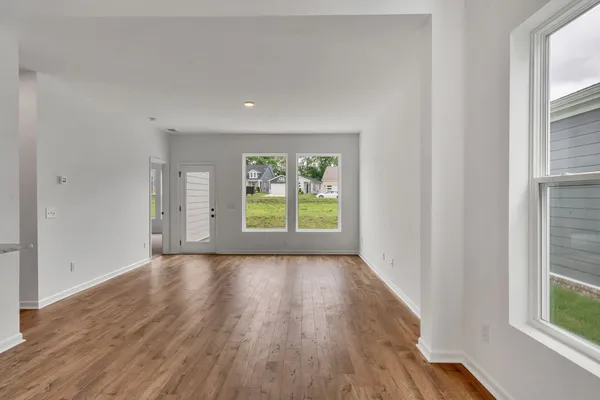 a view of a big room with wooden floor and windows