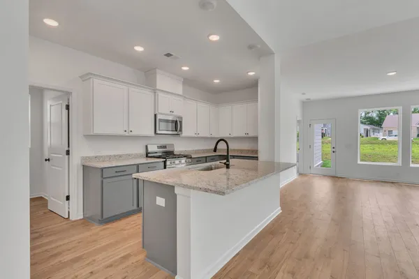 a large kitchen with stainless steel appliances granite countertop a lot of counter space and wooden floors