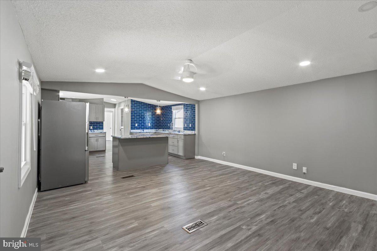 92 Patuxent Mobile Estates Lothian, MD 20711 - Photo 4 of 19 an empty room with wooden floor and a kitchen