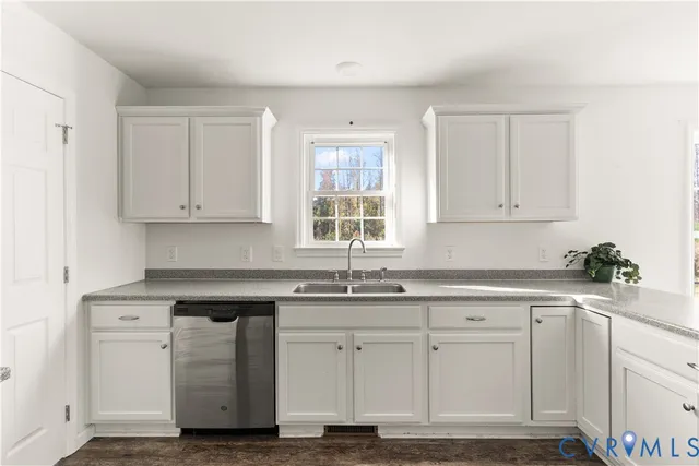 a kitchen with white cabinets appliances a sink and a window