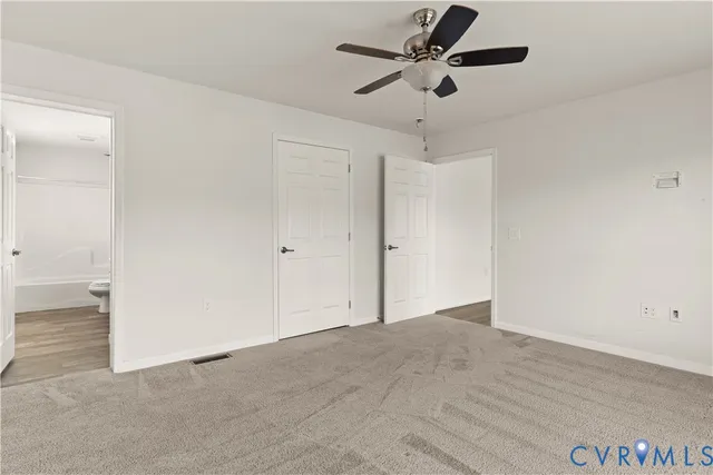 an empty room with a ceiling fan and carpet
