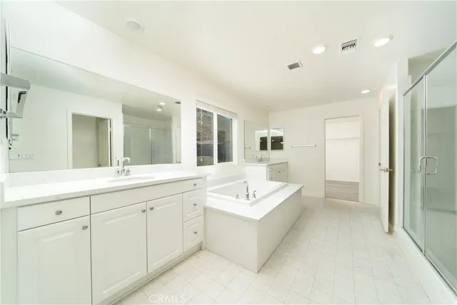 a spacious bathroom with a double vanity sink mirror and bathtub