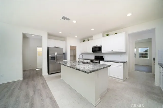 a kitchen with stainless steel appliances kitchen island granite countertop a refrigerator and a stove top oven