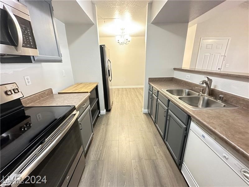 6650 West Warm Springs Road, Unit 2007 Las Vegas, NV 89118 - Photo 11 of 26 Kitchen featuring appliances with stainless steel finishes, gray cabinets, dark wood-type flooring, and a textured ceiling