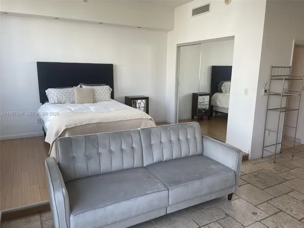 a bedroom with a bed a couch and a window