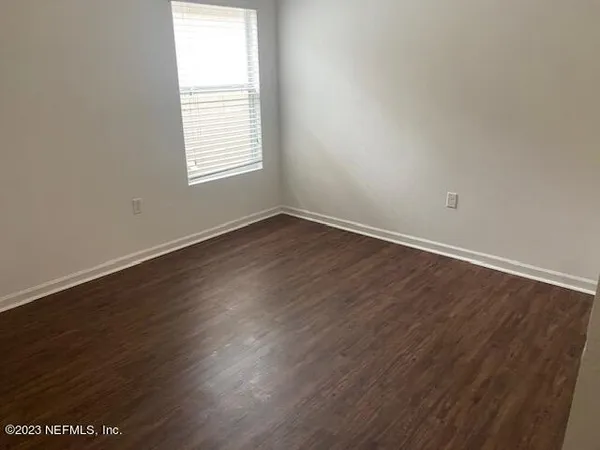 an empty room with wooden floor and window