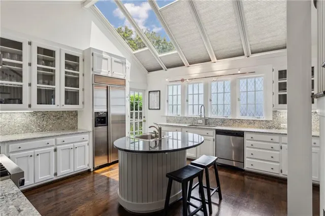 a dining room with stainless steel appliances kitchen island granite countertop a table chairs in it and a window