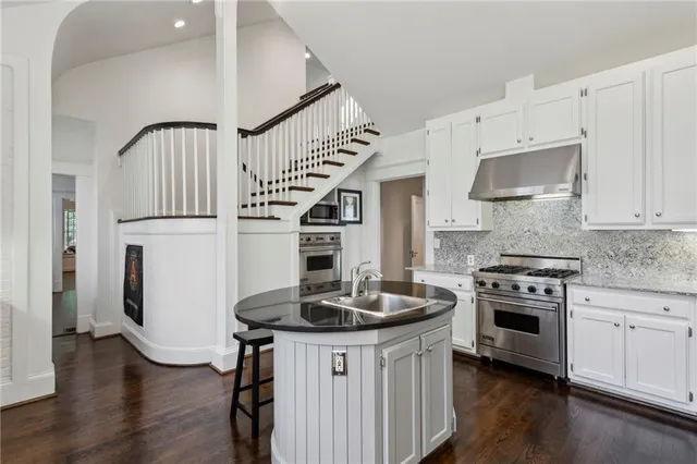 a kitchen with granite countertop a sink stainless steel appliances and white cabinets