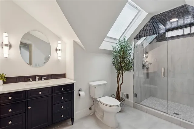 a bathroom with a toilet a sink a glass shower door and a mirror