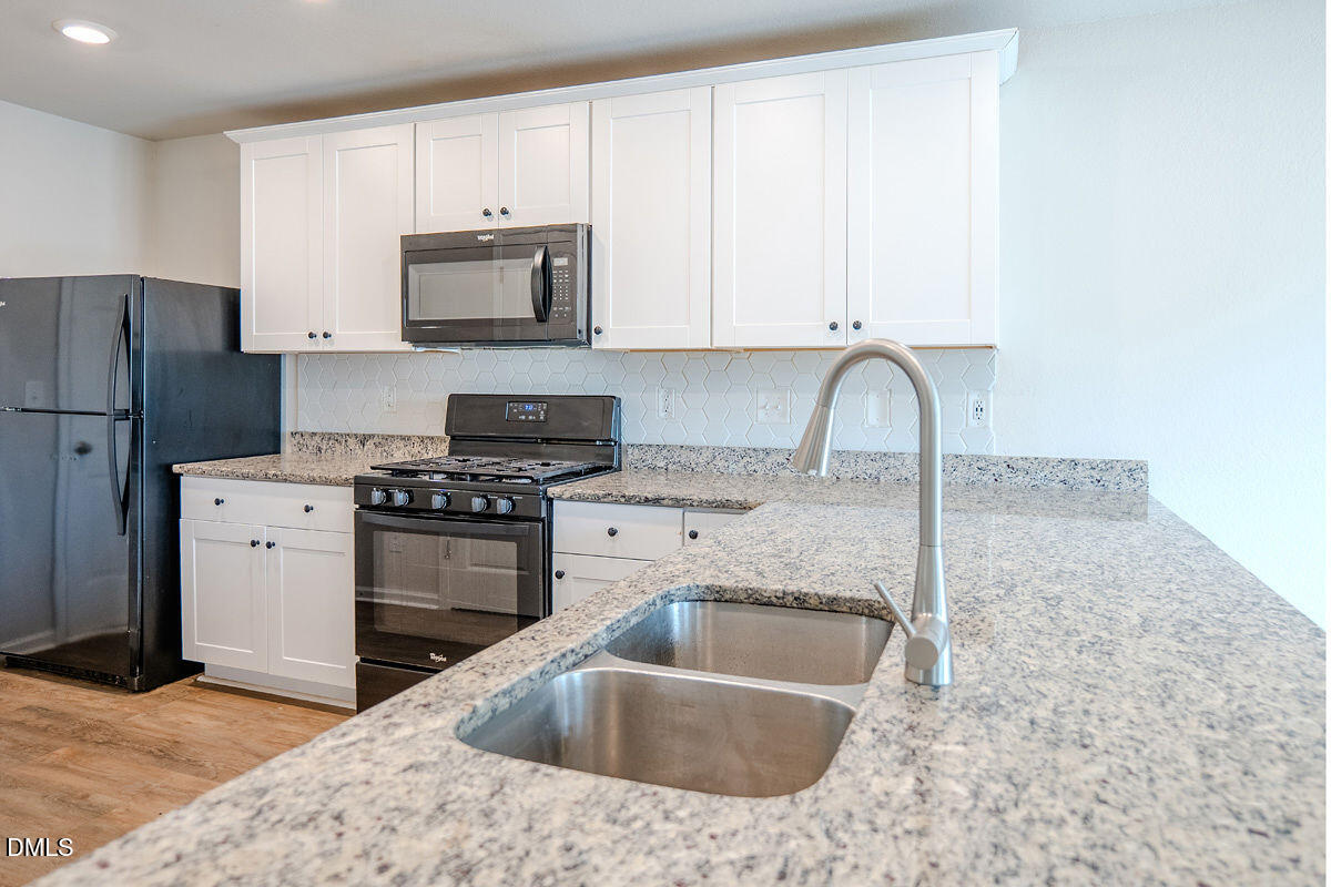 2036 Alderman Way Creedmoor, NC 27522 - Photo 10 of 49 a kitchen with granite countertop a sink stainless steel appliances and white cabinets