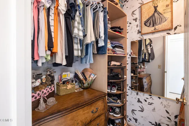 a view of walk in closet with clothes and shoes