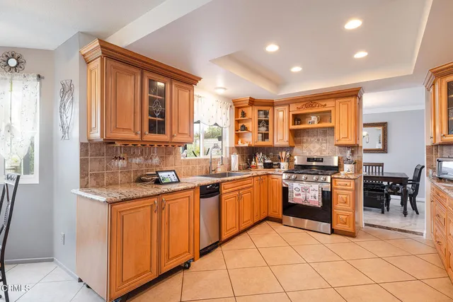 a kitchen with stainless steel appliances granite countertop a stove top oven a sink a dining table and chairs