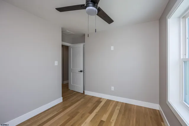 a view of empty room with wooden floor and fan