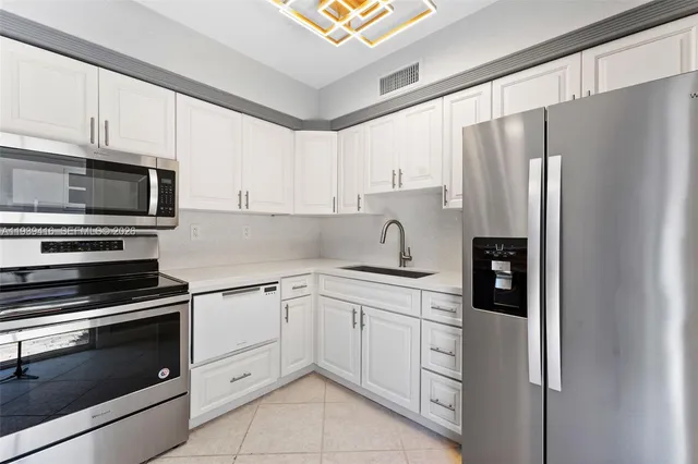 a kitchen with cabinets stainless steel appliances and sink