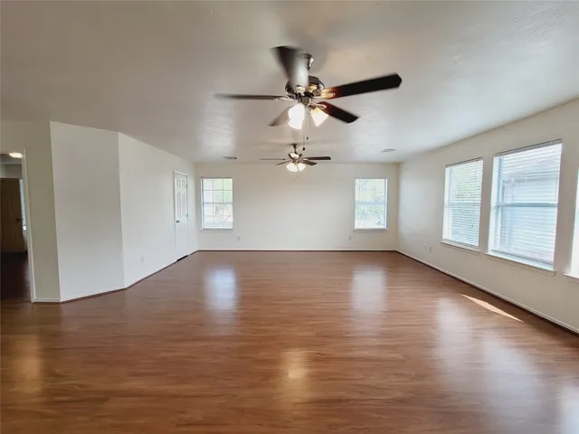 a view of empty room with wooden floor and fan