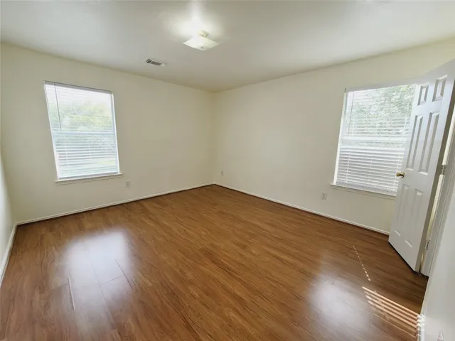 a view of an empty room with wooden floor and a window