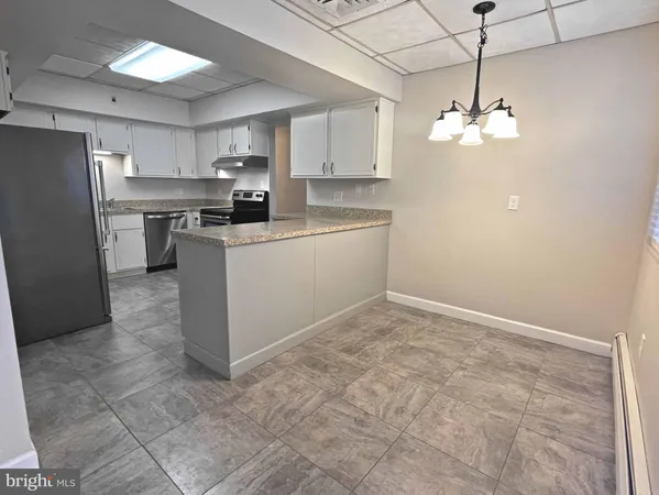 a kitchen with kitchen island white cabinets stainless steel appliances and a chandelier