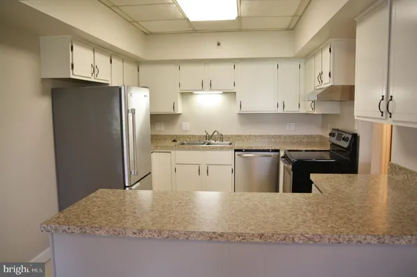 a kitchen with stainless steel appliances granite countertop a sink refrigerator and cabinets