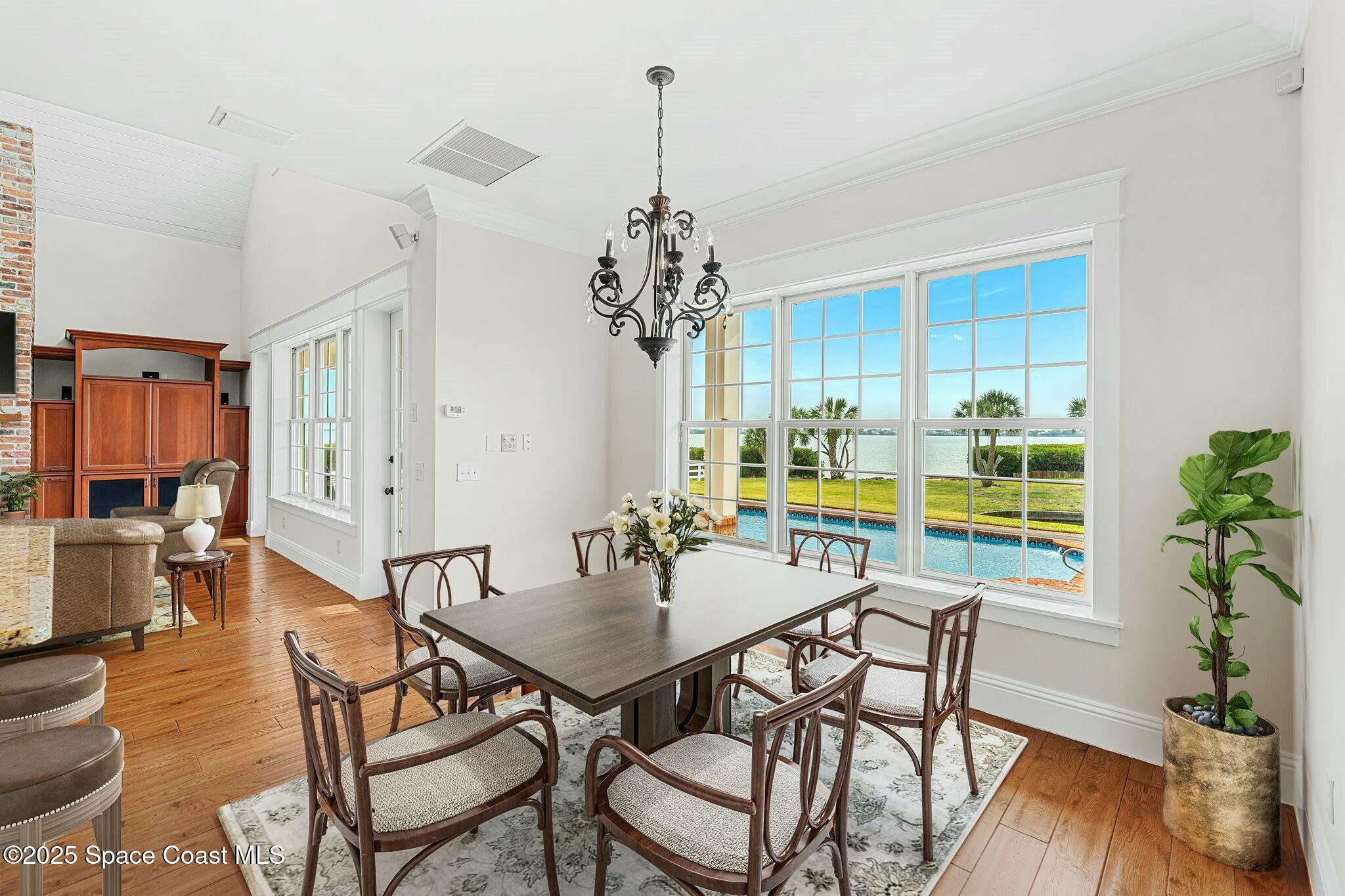 9490 South Tropical Trail Merritt Island, FL 32952 - Photo 21 of 63 a dining room with furniture a chandelier and wooden floor