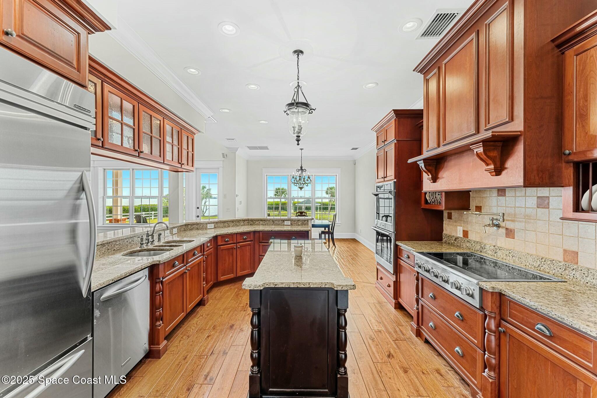 9490 South Tropical Trail Merritt Island, FL 32952 - Photo 25 of 63 a kitchen with stainless steel appliances granite countertop a stove a sink and a refrigerator