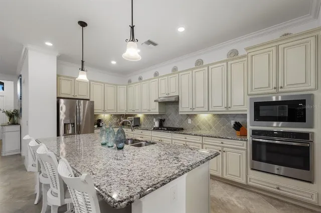 a kitchen with stainless steel appliances granite countertop a sink a stove a refrigerator a center island and cabinets