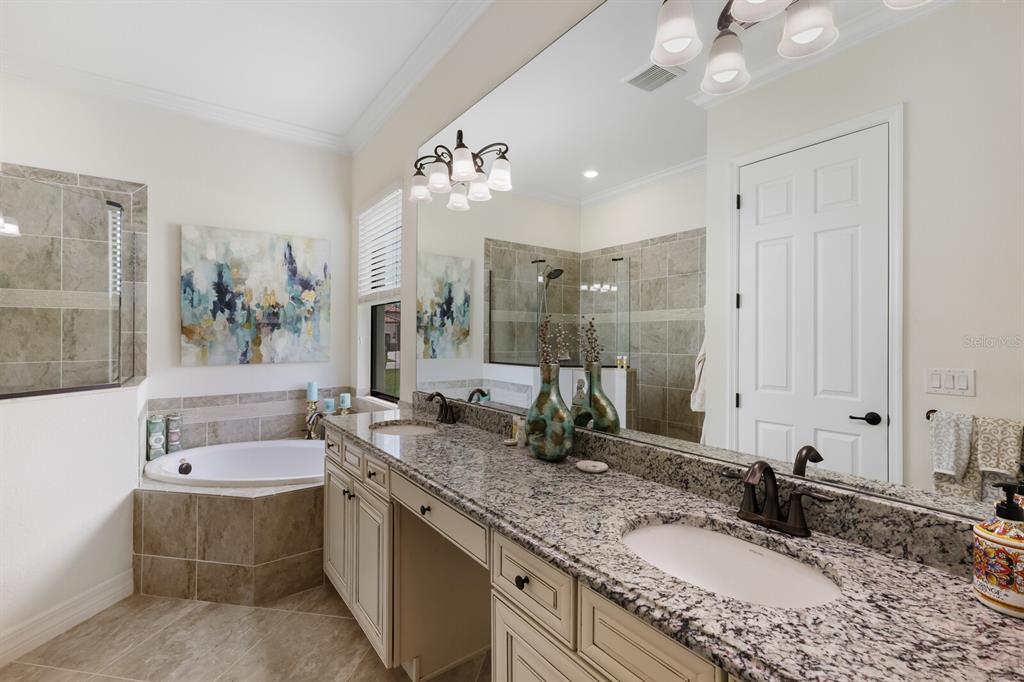 6036 Cessna Run Bradenton, FL 34211 - Photo 22 of 75 a bathroom with a granite countertop double vanity sink a mirror and a bathtub