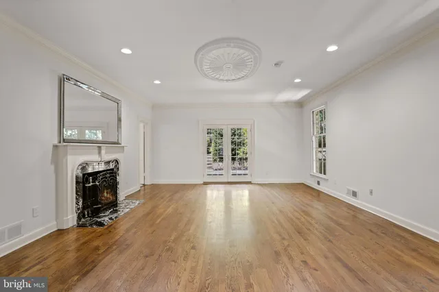 an empty room with fireplace wooden floor and windows