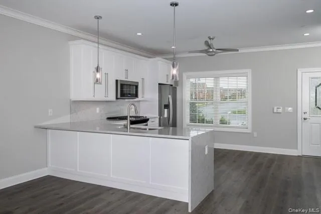 a kitchen with stainless steel appliances granite countertop a sink a stove a refrigerator and island with wooden floor