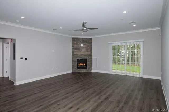 a view of an empty room with wooden floor fireplace and a window