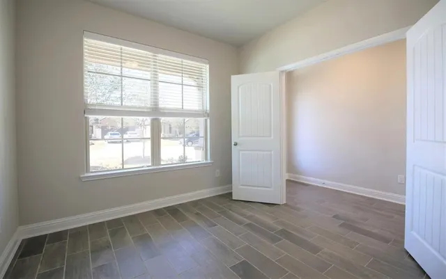 an empty room with wooden floor and windows