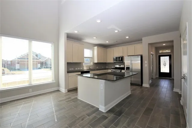 a kitchen with stainless steel appliances granite countertop a stove a sink and a refrigerator