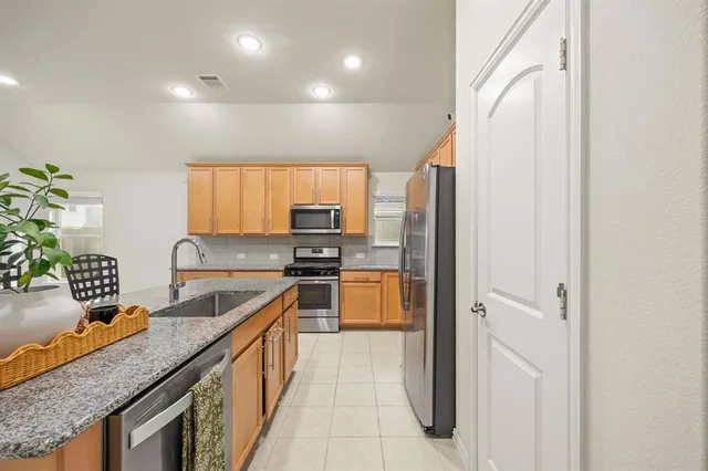 a kitchen with stainless steel appliances granite countertop a sink and a refrigerator