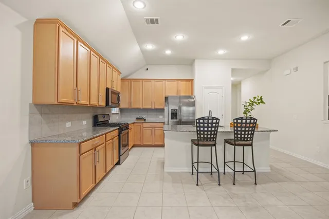 a kitchen with stainless steel appliances granite countertop a stove a sink and a refrigerator