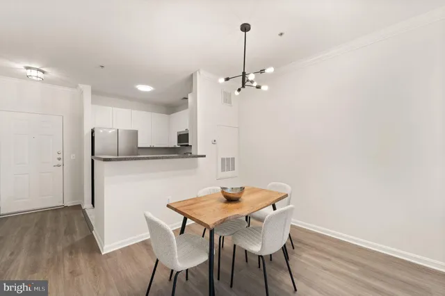 a kitchen with stainless steel appliances a dining table chairs and wooden floor
